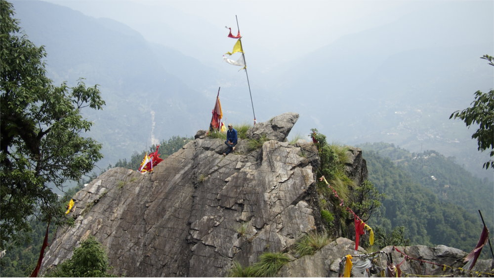 There is a solitary flag. A red herald of the peak of the mountain. It sits among a stone outcropping stark in centre frame with the valley hundreds of metres below visible either side.