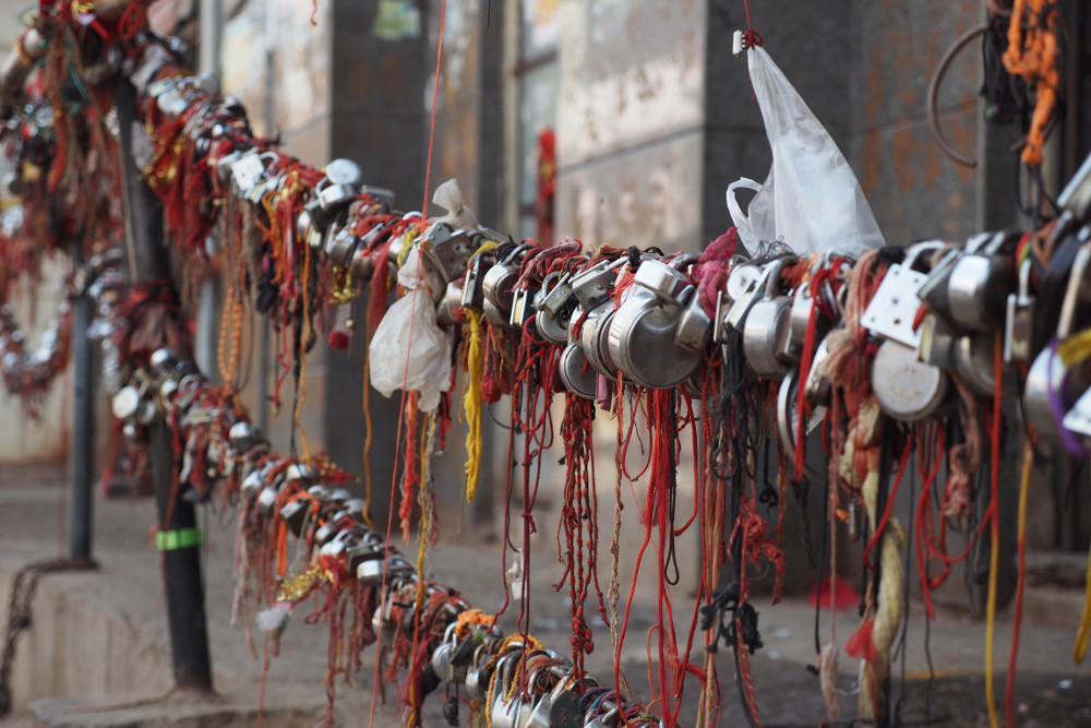 Three fence wires that have been so heavily adorned in locks and prayer string that they droop heavily to the ground.