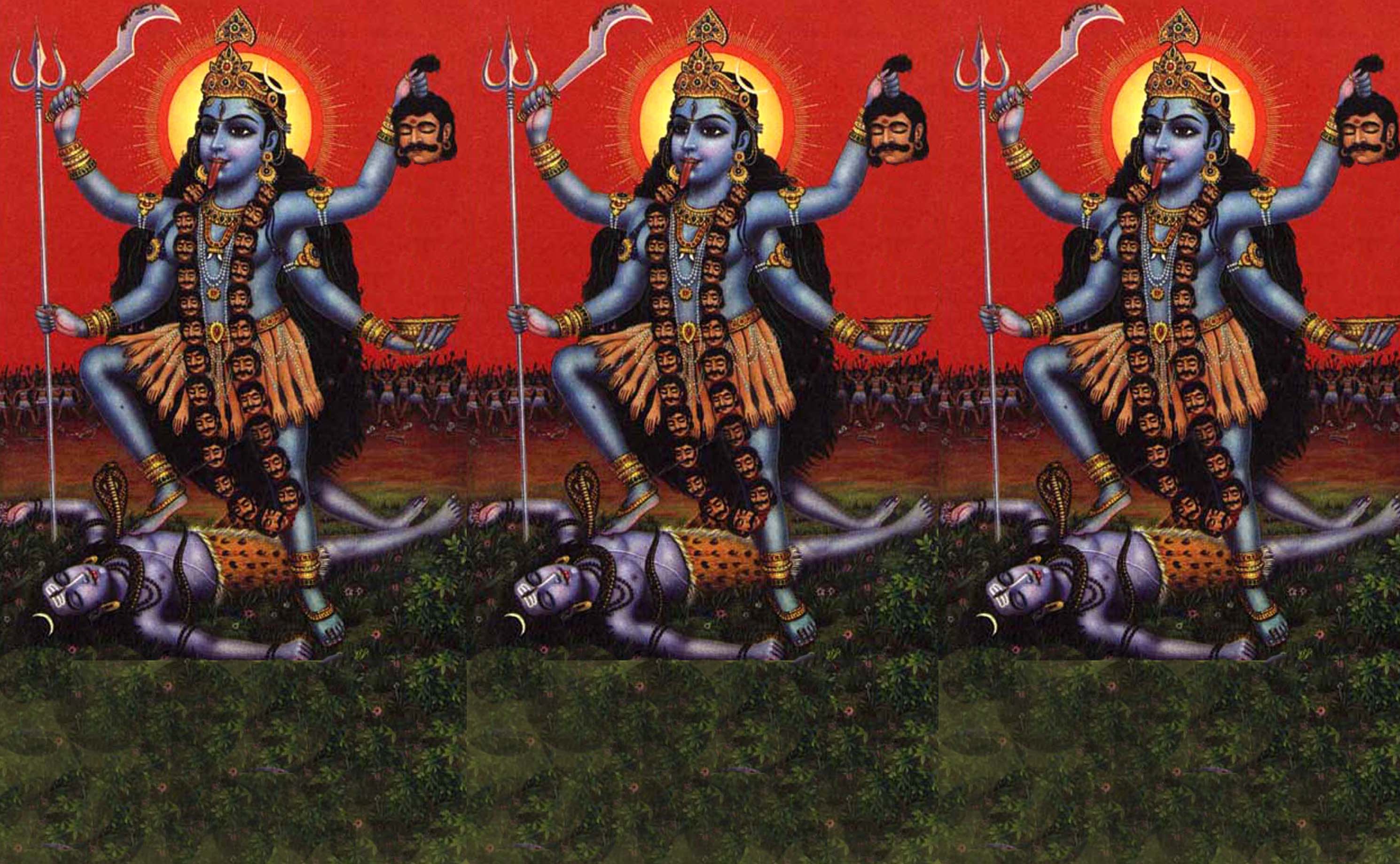 Kali is depicted here with blue skin and a garland of severed heads. She holds a khopesh (saber) and a severed head. Her tongue is obscenely long to catch the blood that drains from the heads. She stands on the body of a sleeping shiva.