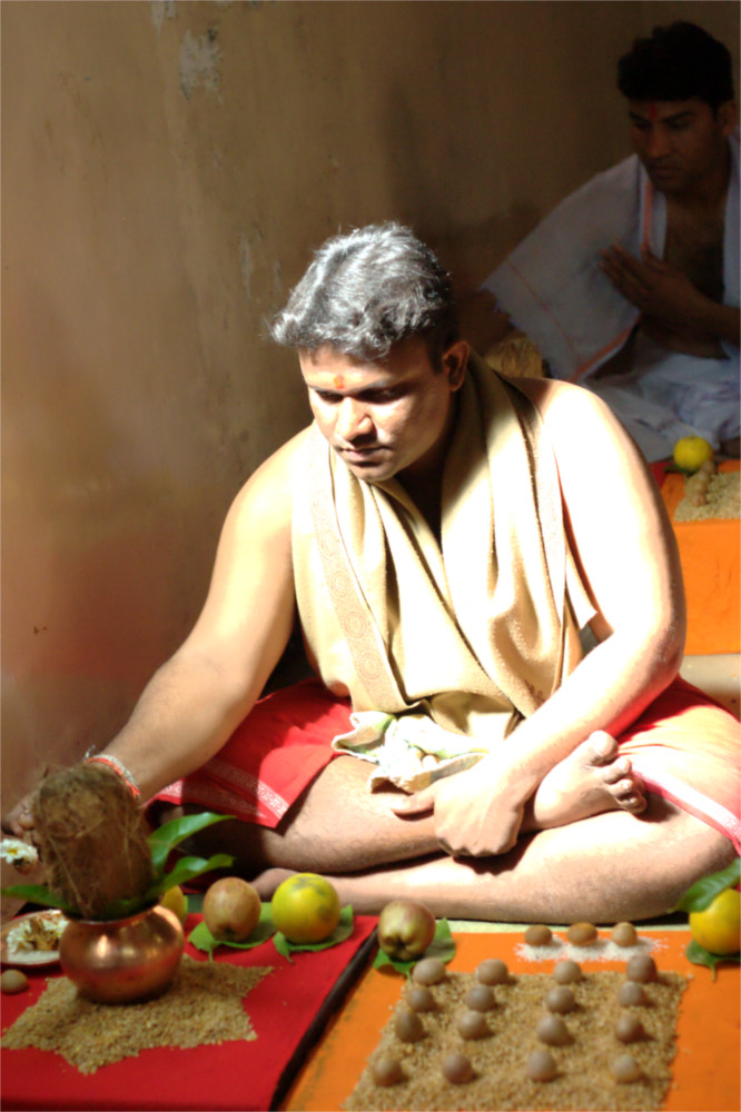 Lone Pandit sits doing Pitru Shanti (a ritual) under a single sunbeam